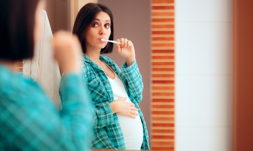 Mujer embarazada cepillándose los dientes.